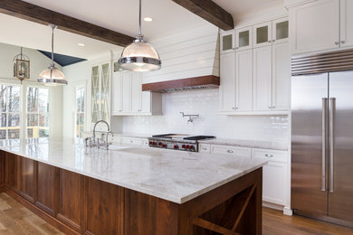 Enclosed kitchen - large farmhouse single-wall light wood floor enclosed kitchen idea in Atlanta with a farmhouse sink, shaker cabinets, white cabinets, quartzite countertops, white backsplash, subway tile backsplash, stainless steel appliances and an island