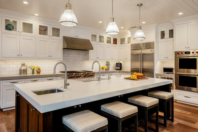 Inspiration for a farmhouse l-shaped medium tone wood floor, brown floor and shiplap ceiling kitchen remodel in San Francisco with an undermount sink, shaker cabinets, white cabinets, white backsplash, subway tile backsplash, stainless steel appliances, an island and white countertops