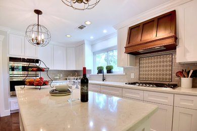 Mid-sized transitional l-shaped medium tone wood floor and brown floor eat-in kitchen photo in Tampa with shaker cabinets, white cabinets, quartz countertops, an island, white countertops, an undermount sink, gray backsplash, subway tile backsplash and stainless steel appliances