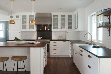 Inspiration for a large farmhouse l-shaped dark wood floor eat-in kitchen remodel in Burlington with a farmhouse sink, recessed-panel cabinets, white cabinets, limestone countertops, white backsplash, subway tile backsplash, stainless steel appliances and an island