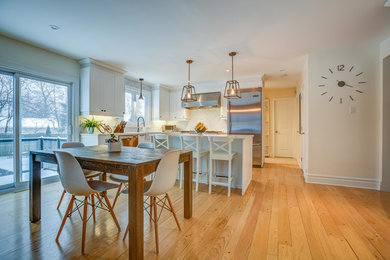 Eat-in kitchen - mid-sized transitional light wood floor eat-in kitchen idea in Montreal with a farmhouse sink, shaker cabinets, white cabinets, white backsplash, marble backsplash, stainless steel appliances, an island, quartz countertops and white countertops