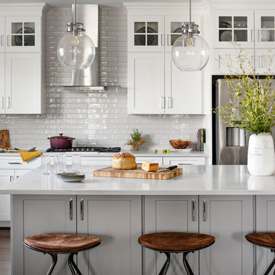 Inspiration for a large country l-shaped dark wood floor and brown floor eat-in kitchen remodel in DC Metro with a farmhouse sink, white cabinets, quartz countertops, white backsplash, subway tile backsplash, stainless steel appliances, an island, white countertops and shaker cabinets