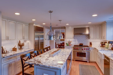 Eat-in kitchen - mid-sized farmhouse u-shaped light wood floor and brown floor eat-in kitchen idea in DC Metro with a farmhouse sink, recessed-panel cabinets, white backsplash, subway tile backsplash, stainless steel appliances, an island, white cabinets, quartzite countertops and white countertops