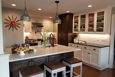 Inspiration for a mid-sized country dark wood floor and brown floor eat-in kitchen remodel in Kansas City with white cabinets, quartz countertops, white backsplash, ceramic backsplash, stainless steel appliances, an island and an undermount sink