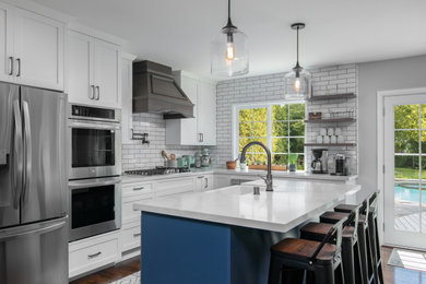 Eat-in kitchen - transitional medium tone wood floor and brown floor eat-in kitchen idea in Los Angeles with shaker cabinets, white cabinets, quartz countertops, white backsplash, porcelain backsplash, an island, white countertops, a farmhouse sink and stainless steel appliances