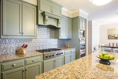 Mid-sized farmhouse galley medium tone wood floor eat-in kitchen photo in New Orleans with a drop-in sink, shaker cabinets, green cabinets, granite countertops, metallic backsplash, metal backsplash, stainless steel appliances and an island