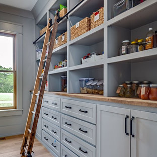 Large farmhouse kitchen pantry pictures - Inspiration for a large cottage single-wall medium tone wood floor and brown floor kitchen pantry remodel in Nashville with wood countertops, a farmhouse sink, shaker cabinets, white cabinets, white backsplash, subway tile backsplash, stainless steel appliances, an island and white countertops