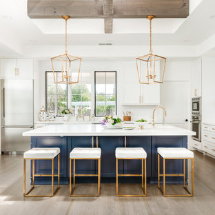 Large farmhouse kitchen designs - Inspiration for a large cottage l-shaped light wood floor and gray floor kitchen remodel in San Francisco with shaker cabinets, blue cabinets, white backsplash, an island, white countertops, a farmhouse sink, quartz countertops, ceramic backsplash and stainless steel appliances