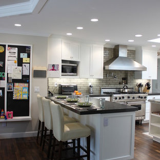 Inspiration for a large country u-shaped eat-in kitchen in San Diego with a farmhouse sink, shaker cabinets, white cabinets, quartzite benchtops, beige splashback, terra-cotta splashback, stainless steel appliances, dark hardwood floors and a peninsula.