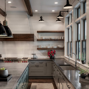 This is an example of a large country u-shaped eat-in kitchen in New York with a single-bowl sink, shaker cabinets, grey cabinets, concrete benchtops, white splashback, timber splashback, stainless steel appliances, dark hardwood floors, with island, brown floor and black benchtop.