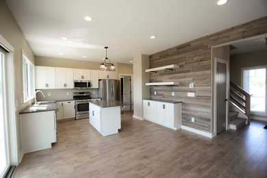 Inspiration for a modern laminate floor and brown floor kitchen remodel in Other with white cabinets, stainless steel appliances and an island