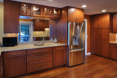 Moderne Wohnküche mit Unterbauwaschbecken, hellbraunen Holzschränken, Granit-Arbeitsplatte, Küchengeräten aus Edelstahl, braunem Holzboden und Halbinsel in Nashville