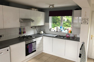 Medium sized modern single-wall open plan kitchen in Hertfordshire with flat-panel cabinets, white cabinets, laminate countertops and grey worktops.