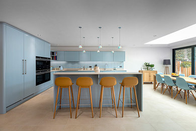 Diseño de cocinas en L minimalista grande abierta con armarios con paneles lisos, puertas de armario azules, encimera de cuarcita y una isla