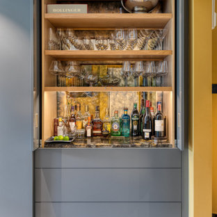 Large contemporary l-shaped open plan kitchen in Hertfordshire with a drop-in sink, louvered cabinets, grey cabinets, granite benchtops, panelled appliances, with island and black benchtop.