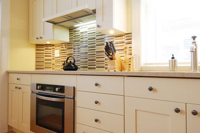 Idéer för att renovera ett litet funkis linjärt kök och matrum, med en undermonterad diskho, skåp i shakerstil, vita skåp, bänkskiva i kvartsit, flerfärgad stänkskydd, glaspanel som stänkskydd, rostfria vitvaror och mellanmörkt trägolv