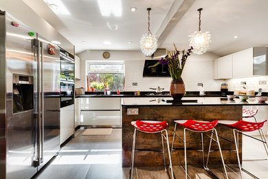 Inspiration for a large modern u-shaped kitchen in London with a built-in sink, white splashback, ceramic splashback, stainless steel appliances, ceramic flooring, an island, grey floors and grey worktops.