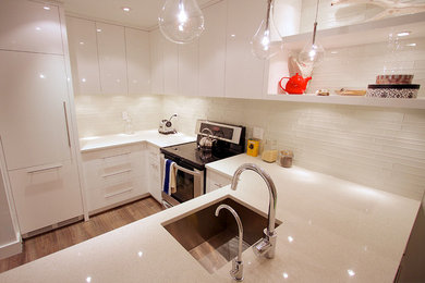 Example of a trendy u-shaped eat-in kitchen design in Vancouver with an integrated sink, flat-panel cabinets, white cabinets, quartz countertops, glass tile backsplash and paneled appliances