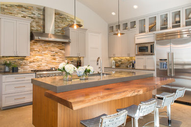 Transitional kitchen photo in Dallas with shaker cabinets, gray cabinets, brown backsplash, stone tile backsplash, stainless steel appliances and an island