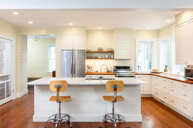 Example of a large beach style l-shaped light wood floor open concept kitchen design in Detroit with an undermount sink, recessed-panel cabinets, white cabinets, granite countertops, white backsplash, ceramic backsplash, stainless steel appliances and an island