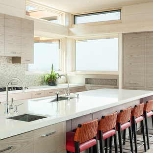 Eat-in kitchen - large modern ceramic tile eat-in kitchen idea in Boston with flat-panel cabinets, light wood cabinets, solid surface countertops, gray backsplash, mosaic tile backsplash, stainless steel appliances and an island