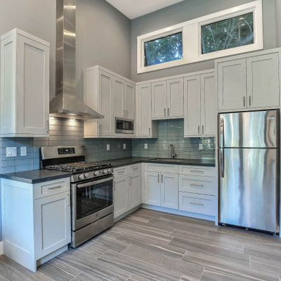 Inspiration for a small modern l-shaped gray floor open concept kitchen remodel in San Francisco with an undermount sink, shaker cabinets, white cabinets, gray backsplash, subway tile backsplash, stainless steel appliances, no island and black countertops