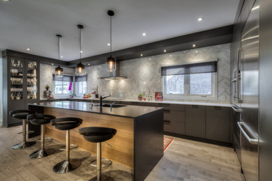 Inspiration for a large modern galley medium tone wood floor and gray floor eat-in kitchen remodel in Toronto with an undermount sink, flat-panel cabinets, gray cabinets, white backsplash, marble backsplash, stainless steel appliances, an island and black countertops