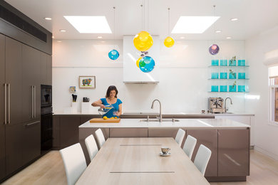 Example of a trendy l-shaped light wood floor eat-in kitchen design in Los Angeles with flat-panel cabinets and an island
