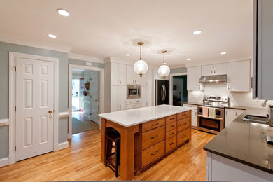 Inspiration for a mid-sized modern galley light wood floor eat-in kitchen remodel in Richmond with an island, a double-bowl sink, raised-panel cabinets, white cabinets, granite countertops, white backsplash and stainless steel appliances
