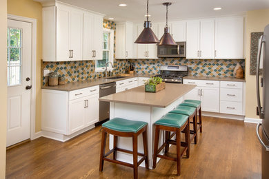 Example of a mid-sized minimalist l-shaped medium tone wood floor enclosed kitchen design in Columbus with an undermount sink, shaker cabinets, white cabinets, quartz countertops, multicolored backsplash, ceramic backsplash, stainless steel appliances and an island