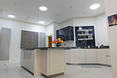 Geschlossene, Zweizeilige, Große Moderne Küche mit Unterbauwaschbecken, flächenbündigen Schrankfronten, weißen Schränken, Granit-Arbeitsplatte, schwarzen Elektrogeräten und Kücheninsel in Buckinghamshire