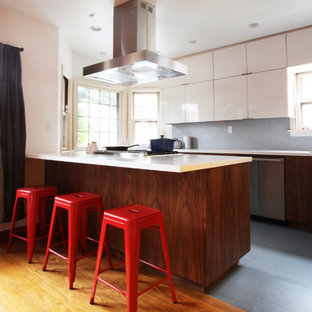 Immagine di una cucina abitabile moderna di medie dimensioni con ante lisce, elettrodomestici in acciaio inossidabile, lavello sottopiano, top in quarzo composito, paraspruzzi blu, paraspruzzi con piastrelle a mosaico, parquet chiaro e penisola