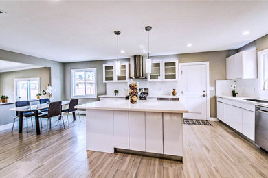 Example of a large trendy l-shaped porcelain tile open concept kitchen design in Orange County with a double-bowl sink, flat-panel cabinets, white cabinets, quartzite countertops, white backsplash, porcelain backsplash, stainless steel appliances and an island
