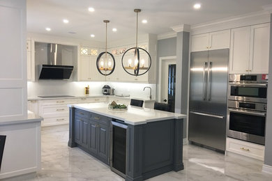 This is an example of a medium sized traditional u-shaped kitchen/diner in Toronto with a submerged sink, recessed-panel cabinets, white cabinets, engineered stone countertops, white splashback, stone slab splashback, stainless steel appliances, porcelain flooring, an island, white floors and white worktops.