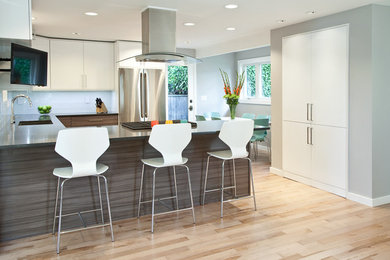 Design ideas for a modern kitchen in Seattle with a submerged sink, flat-panel cabinets, white cabinets, engineered stone countertops, white splashback, glass tiled splashback, stainless steel appliances and light hardwood flooring.