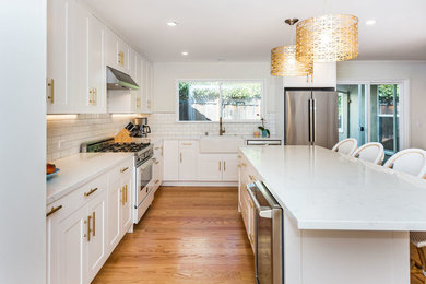Eat-in kitchen - mid-sized contemporary galley light wood floor and brown floor eat-in kitchen idea in San Francisco with a farmhouse sink, shaker cabinets, white cabinets, white backsplash, subway tile backsplash, stainless steel appliances and an island