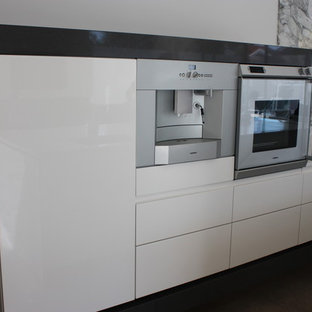 Offene, Einzeilige, Große Moderne Küche mit flächenbündigen Schrankfronten, weißen Schränken, Mineralwerkstoff-Arbeitsplatte, Küchenrückwand in Grau, Rückwand aus Marmor, Küchengeräten aus Edelstahl, Kücheninsel und schwarzem Boden in Melbourne