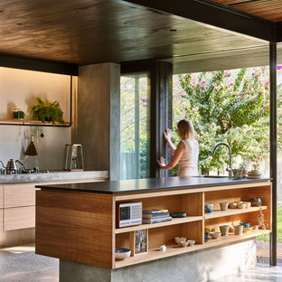 Inspiration for a small contemporary galley kitchen in Brisbane with an undermount sink, flat-panel cabinets, light wood cabinets, granite benchtops, concrete floors, with island, grey floor and black benchtop.