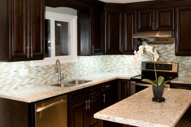 Bild på ett mellanstort funkis kök, med en undermonterad diskho, luckor med upphöjd panel, skåp i mörkt trä, granitbänkskiva, blått stänkskydd, stänkskydd i glaskakel, rostfria vitvaror och en köksö