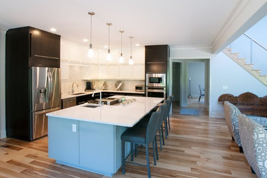 Inspiration for a large modern l-shaped light wood floor eat-in kitchen remodel in New York with flat-panel cabinets, stainless steel appliances and an island