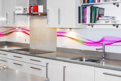 Modelo de cocina minimalista grande con salpicadero multicolor, salpicadero de vidrio templado y electrodomésticos de acero inoxidable