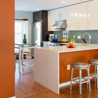 Mid-sized trendy galley medium tone wood floor eat-in kitchen photo in DC Metro with flat-panel cabinets, white cabinets, blue backsplash, an undermount sink, ceramic backsplash, stainless steel appliances and an island