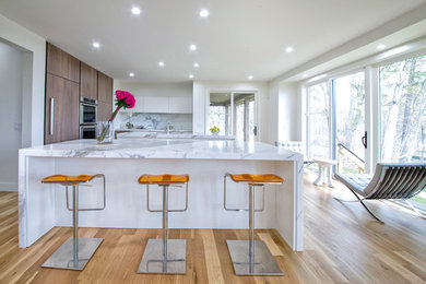 Large minimalist l-shaped light wood floor eat-in kitchen photo in Detroit with an undermount sink, flat-panel cabinets, white cabinets, marble countertops, stone slab backsplash, paneled appliances, two islands and white backsplash