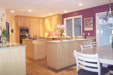 Modern inredning av ett mellanstort kök, med en dubbel diskho, släta luckor, skåp i ljust trä, granitbänkskiva, rostfria vitvaror, mellanmörkt trägolv och en köksö