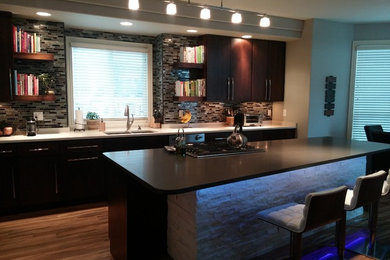 Inspiration for a large contemporary single-wall medium tone wood floor and brown floor open concept kitchen remodel in Denver with an undermount sink, flat-panel cabinets, dark wood cabinets, quartz countertops, multicolored backsplash, glass tile backsplash, stainless steel appliances and an island