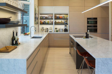 Example of a mid-sized minimalist u-shaped light wood floor eat-in kitchen design in Minneapolis with an undermount sink, flat-panel cabinets, light wood cabinets, marble countertops, white backsplash, paneled appliances and an island
