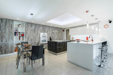 Example of a large minimalist ceramic tile eat-in kitchen design in Miami with a double-bowl sink, flat-panel cabinets, gray cabinets, quartz countertops, white backsplash, ceramic backsplash, white appliances and an island