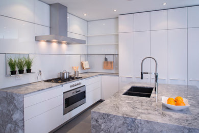 Inspiration for a mid-sized modern u-shaped porcelain tile enclosed kitchen remodel in Calgary with an undermount sink, flat-panel cabinets, white cabinets, granite countertops, white backsplash, glass sheet backsplash, stainless steel appliances and an island