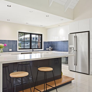 Design ideas for a contemporary l-shaped kitchen in Gold Coast - Tweed with an undermount sink, flat-panel cabinets, white cabinets, blue splashback, stainless steel appliances, with island and white floor.