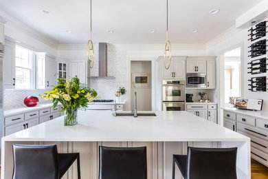 Mid-sized transitional u-shaped medium tone wood floor and brown floor kitchen photo in Raleigh with raised-panel cabinets, quartzite countertops, marble backsplash, stainless steel appliances, an island, white countertops, an undermount sink, gray cabinets and gray backsplash